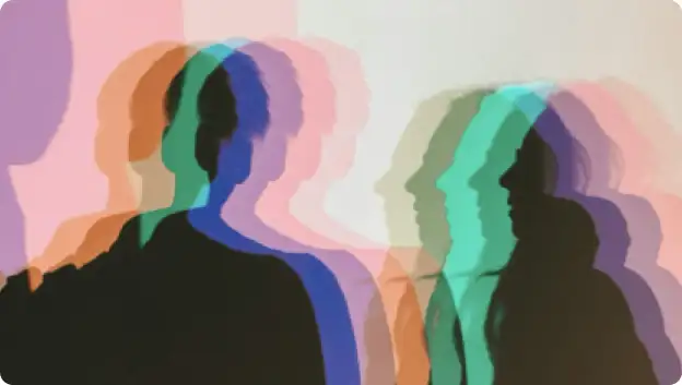 A blurred image of multiple colored silhouettes of people, creating a layered effect with hues of pink, blue, green, and purple against a light background. The silhouettes appear to be in various poses or positions, contributing to a dynamic and abstract visual representation.