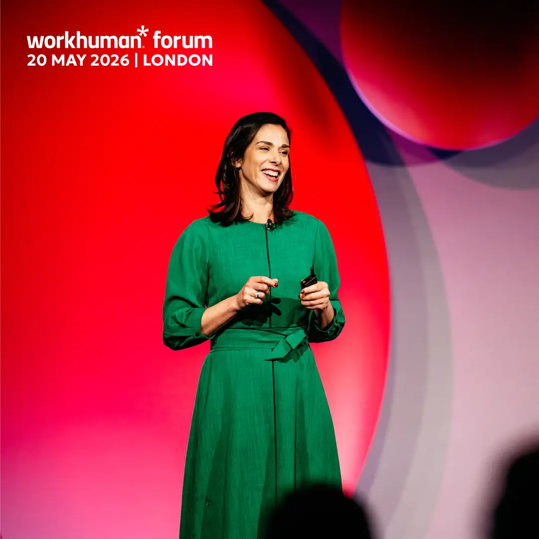 A woman in a green dress stands on stage, smiling while holding a microphone. She appears to be speaking to an audience. The background features vivid colors, including red and hints of other shades. At the top of the image, text displays the event title "workhuman forum" along with the date "20 MAY 2026" and location "LONDON."