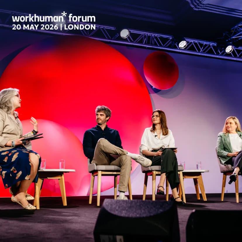 A panel discussion at the Workhuman Forum features four speakers seated on stage. The event is set against a backdrop with bold, circular designs in shades of red and blue. The speakers include a woman on the left holding a microphone and engaging with the audience, while the others listen attentively. A text overlay indicates the event name, "workhuman* forum," along with the date and location: "20 MAY 2026 | LONDON."